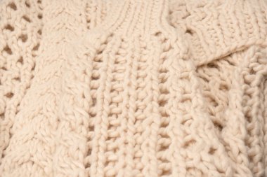 A fragment of beige knitted fabric, knitted from white sheep wool. Knitted background. 