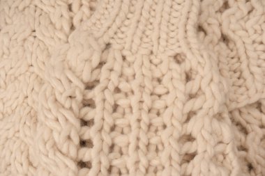 A fragment of beige knitted fabric, knitted from white sheep wool. Knitted background. 
