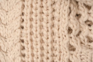 A fragment of beige knitted fabric, knitted from white sheep wool. Knitted background. 