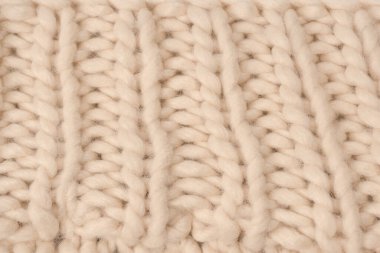 A fragment of beige knitted fabric, knitted from white sheep wool. Knitted background. 