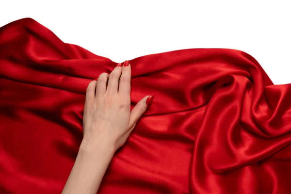 stock image A woman's hand with red nails is trying to rip off  red silk fabric. 