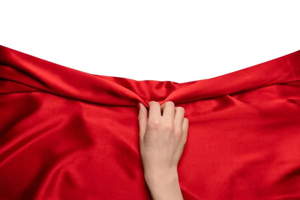 stock image A woman's hand with red nails is trying to rip off  red silk fabric. 