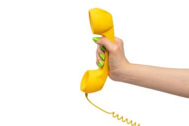 Beyaz arka planda izole edilmiş yeşil tırnaklı kadın eli sarı cep telefonu. Boşluğu kopyala.