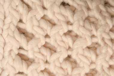 A fragment of beige knitted fabric, knitted from white sheep wool. Knitted background. 