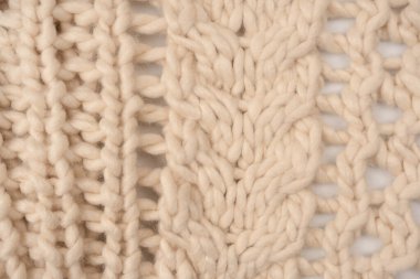 A fragment of beige knitted fabric, knitted from white sheep wool. Knitted background. 