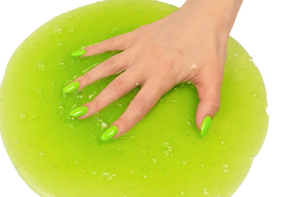 白い背景に隔離された緑の爪を持つ女性の手の中の緑のスライムおもちゃ — ストック写真