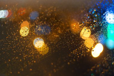 Yağmur damlaları ve ışıklarla bulanık arkaplan.