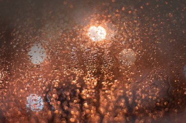 Yağmur damlaları ve ışıklarla bulanık arkaplan.