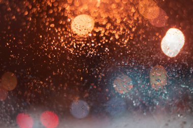Yağmur damlaları ve ışıklarla bulanık arkaplan.