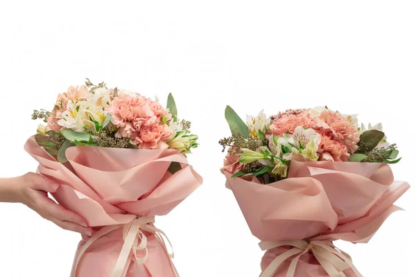Bouquet of  soft pink flowers in pink wrapping paper in woman hands isolated on white background.