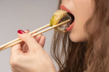 Kırmızı tırnaklı genç kadın suşi yiyor..