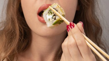 Kırmızı tırnaklı genç kadın suşi yiyor..