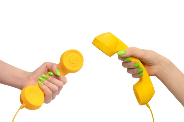 Stock image Yellow handset in woman hand with green nails isolated on a white background. Copy space.