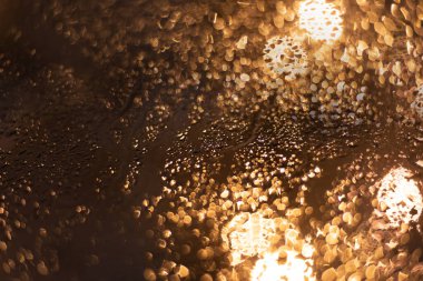 Yağmur damlaları ve ışıklarla bulanık arkaplan.