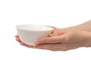 Kadın eli beyaz bir arka planda izole edilmiş seramik bir kase tutuyor.. 