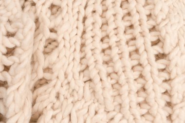 A fragment of beige knitted fabric, knitted from white sheep wool. Knitted background. 