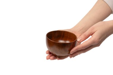 Kadın eli beyaz arka planda izole edilmiş ahşap bir kase tutuyor.. 