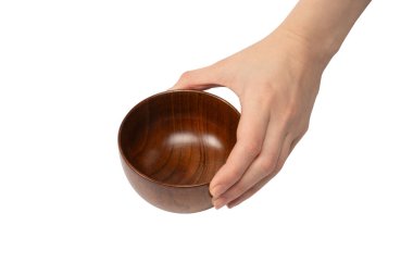 Kadın eli beyaz arka planda izole edilmiş ahşap bir kase tutuyor.. 