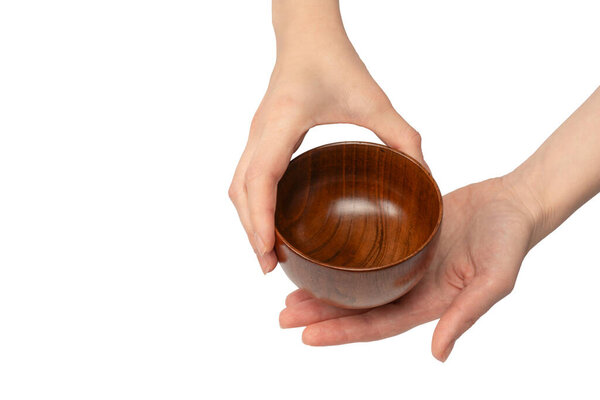 Женская рука держит деревянную чашу на белом фоне. 