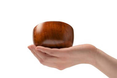 Kadın eli beyaz arka planda izole edilmiş ahşap bir kase tutuyor.. 