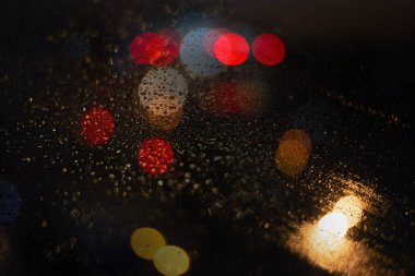 Yağmur damlaları ve ışıklarla bulanık arkaplan.