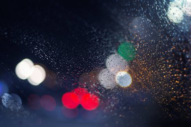 Yağmur damlaları ve ışıklarla bulanık arkaplan.