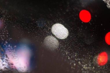 Yağmur damlaları ve ışıklarla bulanık arkaplan.