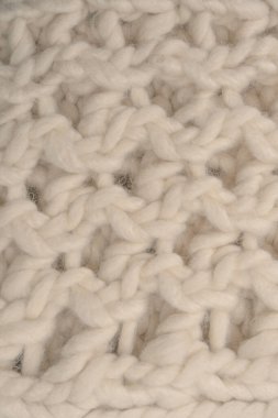 A fragment of beige knitted fabric, knitted from white sheep wool. Knitted background. 