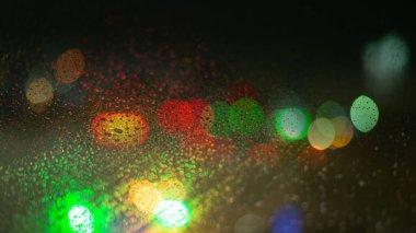 Yağmur damlaları ve ışıklarla bulanık arkaplan.