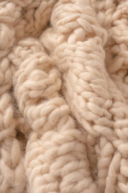 A fragment of beige knitted fabric, knitted from white sheep wool. Knitted background. 