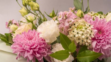 Üzerinde pembe güller, kasımpatı ve frezya çiçeği olan bir buket çiçek beyaz bir arka planda izole edilmiş vazoda.. 