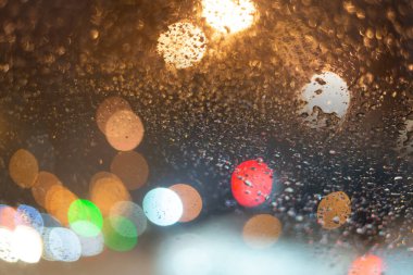 Yağmur damlaları ve ışıklarla bulanık arkaplan.