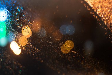 Yağmur damlaları ve ışıklarla bulanık arkaplan.