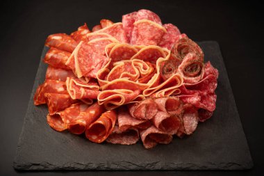 Tahtada farklı et parçaları var. Siyah bir arkaplanda.