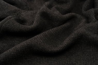 Arka plan olarak koyu gri süveter dokusu. Örgü desenli. Üst görünüm. 