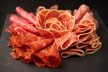 Tahtada farklı et parçaları var. Siyah bir arkaplanda.