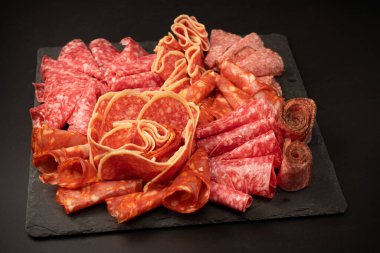 Tahtada farklı et parçaları var. Siyah bir arkaplanda.