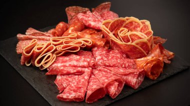 Tahtada farklı et parçaları var. Siyah bir arkaplanda.