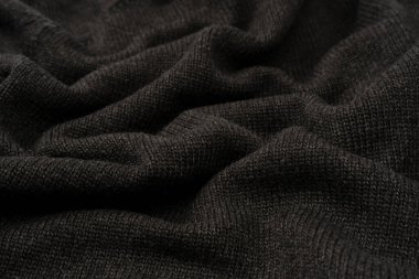 Arka plan olarak koyu gri süveter dokusu. Örgü desenli. Üst görünüm. 