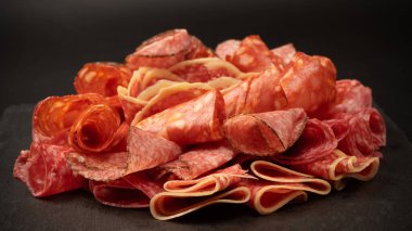 Tahtada farklı et parçaları var. Siyah bir arkaplanda.