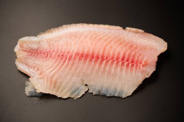 Siyah arkaplanda taze tilapia filetosu, üst görünüm. 
