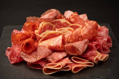 Tahtada farklı et parçaları var. Siyah bir arkaplanda.