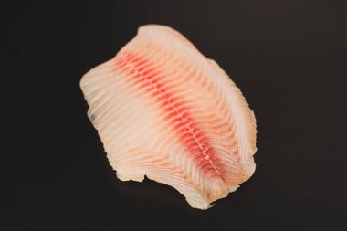 Siyah arkaplanda taze tilapia filetosu, üst görünüm. 