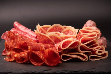 Tahtada farklı et parçaları var. Siyah bir arkaplanda.