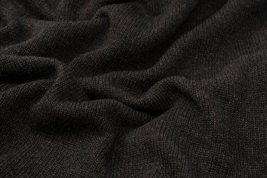 Arka plan olarak koyu gri süveter dokusu. Örgü desenli. Üst görünüm. 