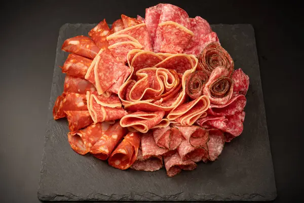 Tahtada farklı et parçaları var. Siyah bir arkaplanda.