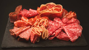 Tahtada farklı et parçaları var. Siyah bir arkaplanda.