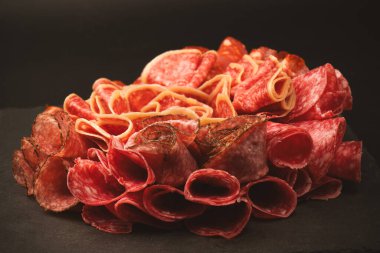 Tahtada farklı et parçaları var. Siyah bir arkaplanda.