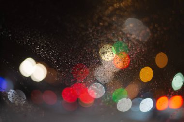 Yağmur damlaları ve ışıklarla bulanık arkaplan.