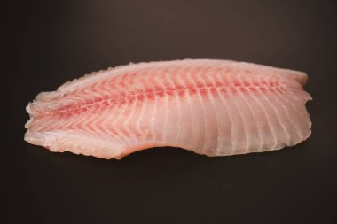 Siyah arkaplanda taze tilapia filetosu, üst görünüm. 